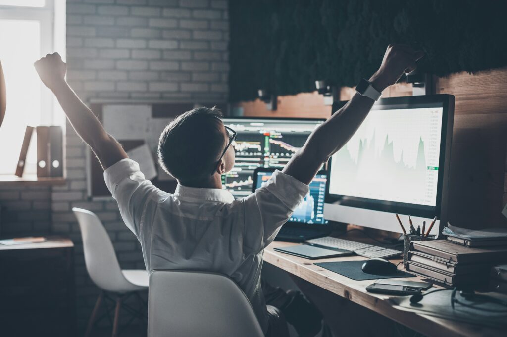 a man sitting at a desk with his arms raised